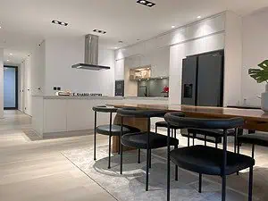 Luxury home kitchen in Sri Lanka with European-style design, featuring a white island with gas hob, sleek dining area, integrated appliances, and modern black fridge