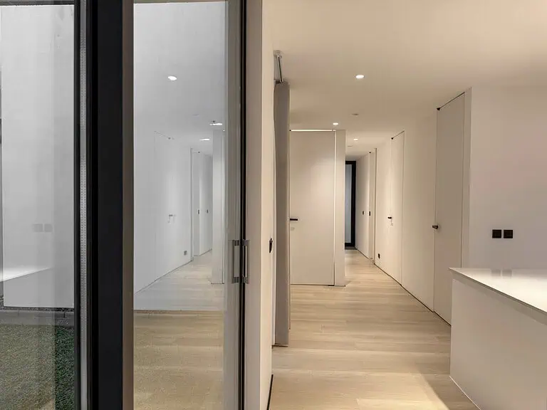 View from the side of a modern kitchen with large sliding windows looking in to the main hallway