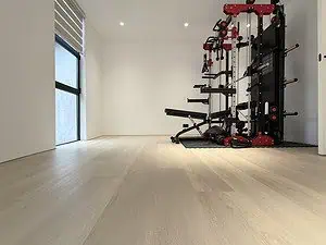 A recreation room in a modern home with fitness equipment in the back and window with a black frame