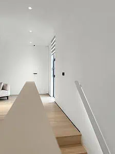 A living room at a staircase with a white wall with a white railing