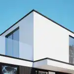 3D render of the upper floor of villa AK with a white rendered facade, black framed windows, and light blue sky