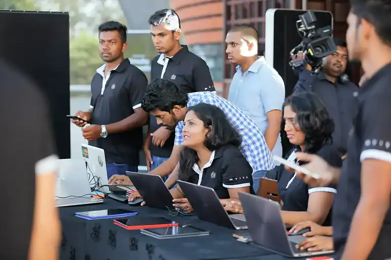 MVIVO staff managing event registration on laptops at a check-in counter, with guests arriving in the background