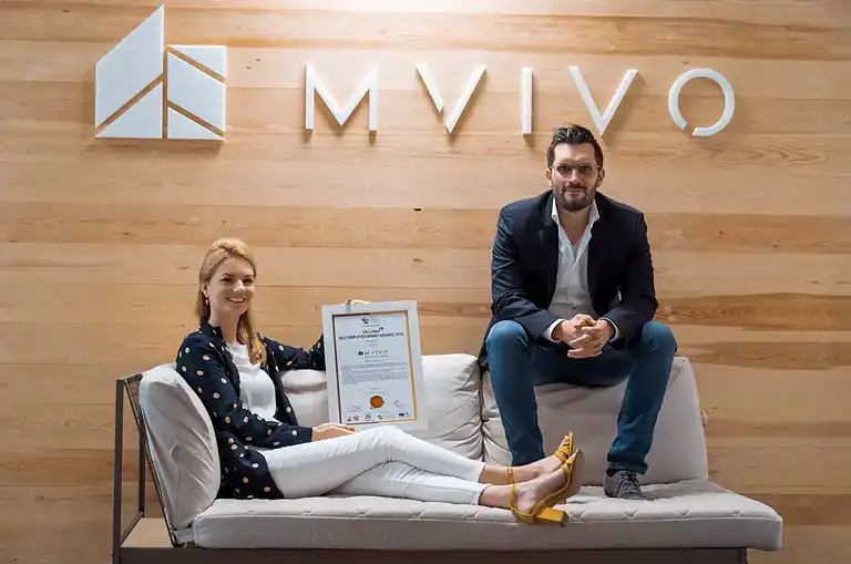 MVIVO founders seated in front of the company logo, holding a framed award for Best Employer Brand