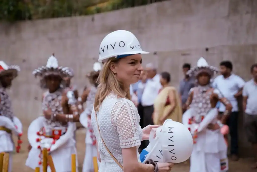 MVIVO team member holding a branded safety helmet at a construction site during a Sri Lankan traditional ceremony