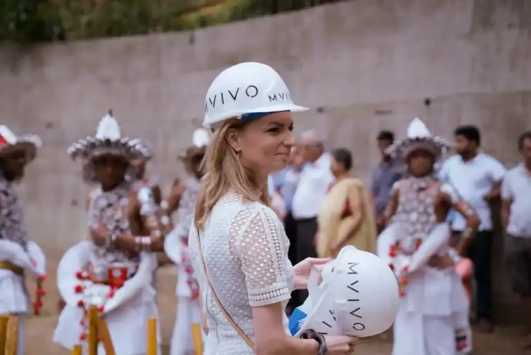 MVIVO team member holding a branded safety helmet at a construction site during a Sri Lankan traditional ceremony