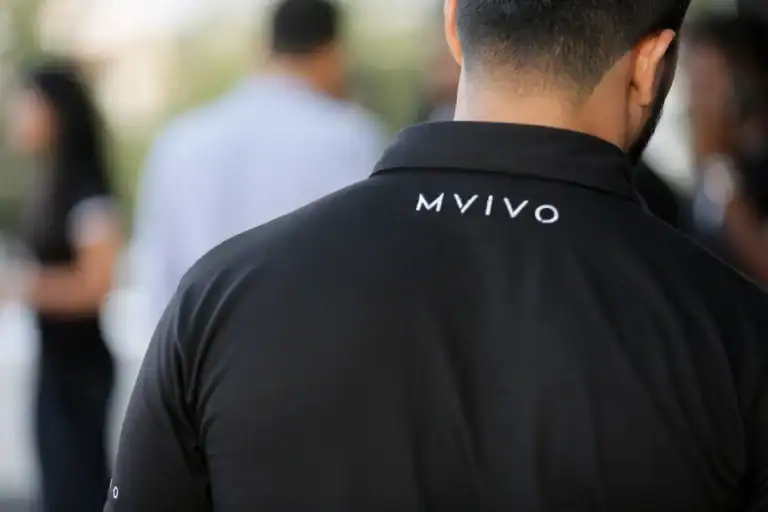 Close-up of the back of an MVIVO staff member wearing a black polo shirt with the MVIVO logo