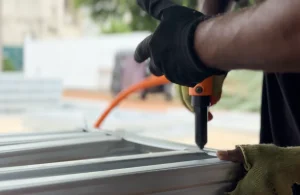 Close-up of a worker riveting a galvanised light steel frame during home construction