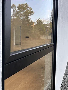 Close-up of a tilt and turn window with black aluminium frame in a stucco wall
