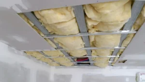 Ceiling insulation installed between metal framing in a construction site.