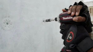 Worker using power drill to secure cavity wall drainage layer.