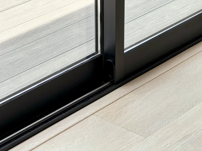 Close-up of black aluminium sliding door with wood flooring in a contemporary home in Sri Lanka.