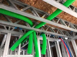 MEP installation with green ventilation ducts inside light steel frame construction.