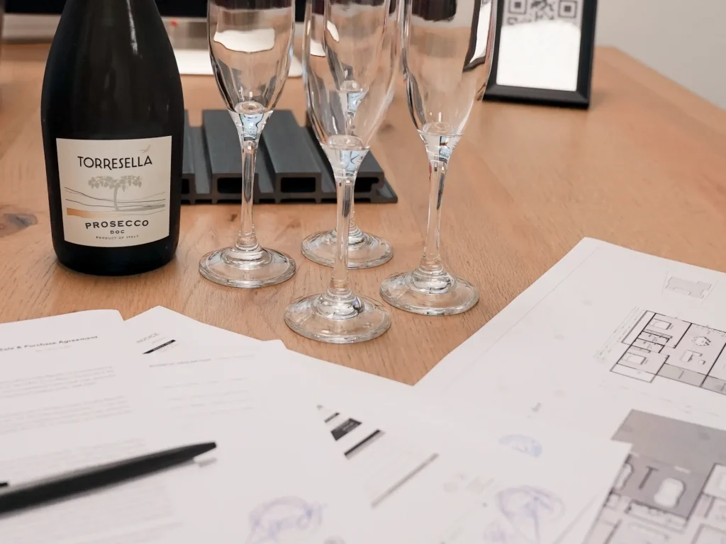 Luxury villa final design and budgeting session with floor plans, agreements and a bottle of prosecco with four glasses