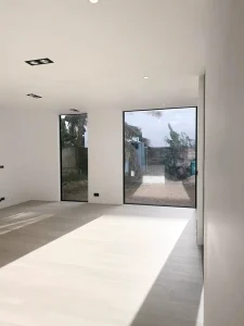 Spacious living room with large windows and light wooden flooring.