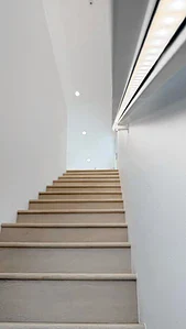 Staircase with light timber steps and LED handrail lighting in a minimalist interior.
