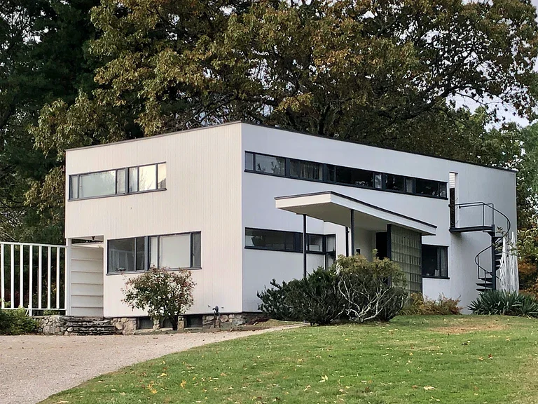 Walter Gropius House in Massachusetts, a white rectangular Bauhaus residence with horizontal windows, flat roof, and minimalist façade set among trees and greenery.